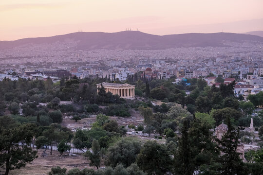 Sunset view of the Temple of Hephaestus standing among trees in the Ancient Agora, Athens, Greece
