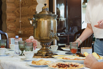 Traditional tea drinking with a samovar, cups, and homemade pancakes on the table.