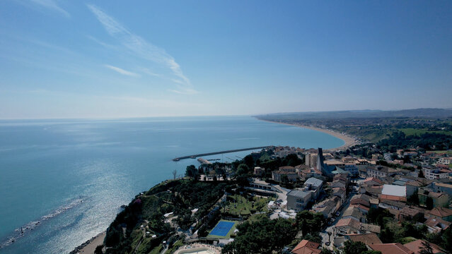 Stunning Aerial View Captures the Coastal Beauty of Numana Italy Showing Buildings and Landmarks Dotting the Adriatic Sea Shoreline Under a Clear Blue Sky
