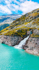 Austria, 08-2025 : waterfall in the weißsee reservoir lake. Mountain and blue sky in background.