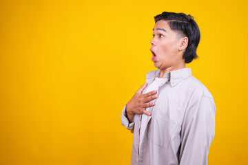 Shocked Young Asian Man Standing With Hand On Chest While Looking To Side