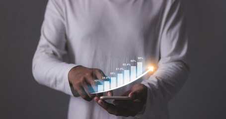 Young man with smartphone hand touching to visualize money growth The phone screen displays graphs and charts showing increasing investment and savings trends, along with an increased account balance