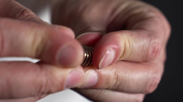 A man compresses a spring with his fingers.
A sturdy metal spring in the hands of a craftsman.
A man compresses a strong metal spring.
Spring, shock absorption, component, macro