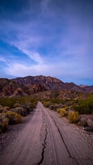 Dusty road leading to mountains at twilight