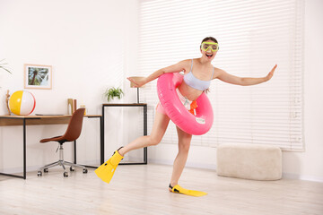 Happy woman in diving mask and flippers with inflatable ring having fun at home. Dreaming about vacation at sea © New Africa