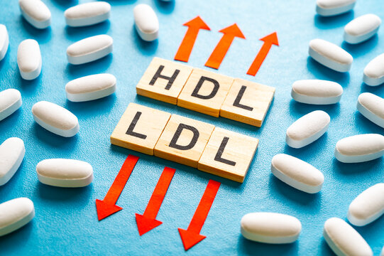 Concept of increasing HDL cholesterol and decreasing LDL cholesterol, terms composed with wooden alphabet and up and down arrows.