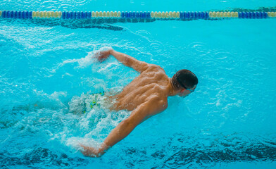Professional Swimmer Performing Butterfly Stroke &ndash; Speed, Power and Determination. Swimming Competition &ndash; Athlete in Butterfly Style Training in Blue Water Pool