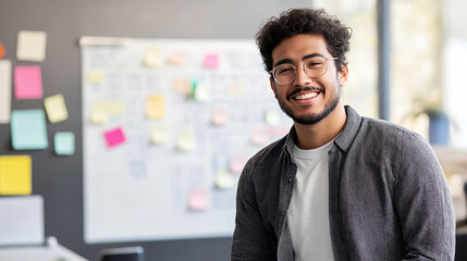 Young Latino entrepreneur engaged in brainstorming session near a whiteboard with sticky notes in a modern office
