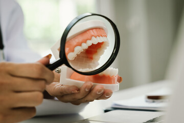 A doctor writes notes on a clipboard beside a dental model, symbolizing oral health care, treatment planning, and patient education.