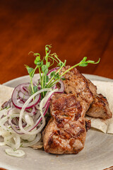 Grilled meat with fresh onion rings and herbs on a plate