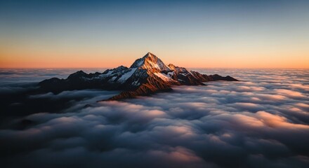 Sunset illuminates a snow-capped mountain peak rising majestically above a sea of clouds