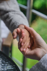 A tender moment of connection as two hands gently touch each other.