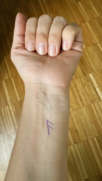 Close-Up of a Hand with the Purple Ansuz Rune Drawn on the Inner Wrist, Highlighting a Simple Design against a Natural Skin Background