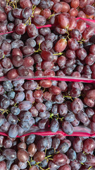Close-Up View of Fresh, Juicy Red and Black Grapes Piled Together in a Vibrant Display, Showcasing Their Natural Shine and Plumpness with Green Stems