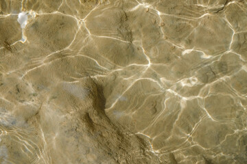 Background texture of sparkling sunlight on the bottom of a sparkling river. For graphic design and banners