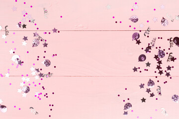 Party pink confetti on wooden background, top view