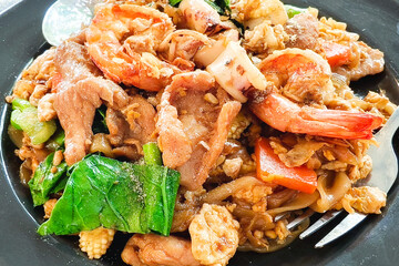 Pad See Ew Delight: This image showcases a vibrant plate of Pad See Ew, a popular Thai dish, filled with enticing ingredients such as shrimp, pork, and vegetables.
