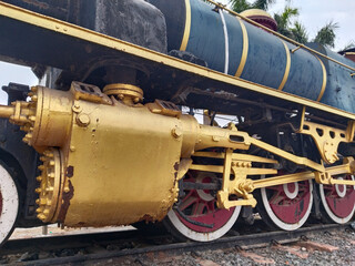 Close-up view of the lower part of a vintage steam locomotive showing metal wheels, rods, and mechanical linkages from side angle, highlighting engineering design and industrial heritage
