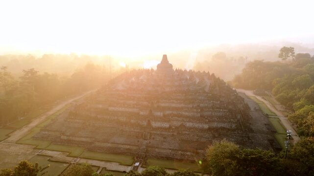 Aerial view of Borobudur Temple at sunrise in Central Java, Indonesia. Ancient Buddhist monument covered in mystical morning mist. UNESCO World Heritage Site, culture, history, and travel themes.
