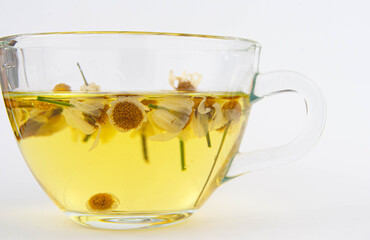 Transparent glass cup filled with chamomile tea on white background.