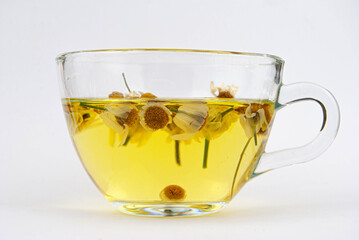 Transparent glass cup filled with chamomile tea on white background.