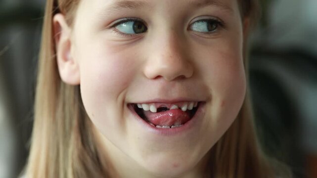 The girl playfully sticks out her tongue and smiles, showing the missing tooth in turn. Dantist
