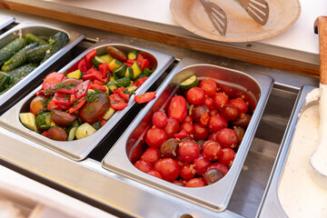 Fresh vegetable salads, pickled cucumbers and tomatoes, and other snacks on a buffet table.