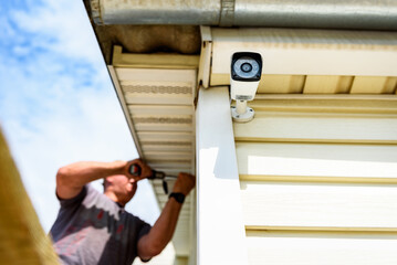 Man installing security camera exterior on the wall of the house