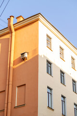 Air conditioners on the facade of a yellow house against a blue sky. An air ventilation and cooling system and air purification technologies are installed. split system.