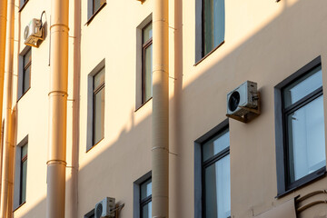 Air conditioners on the facade of yellow historical house. An air ventilation and cooling system and air purification technologies are installed. split system. cooling in hot weather. climate.