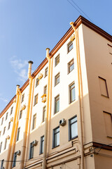 Air conditioners on the facade of a yellow house against a blue sky. An air ventilation and cooling system and air purification technologies are installed. split system.