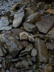 Wet natural stones stacked together in outdoor environment, symbolizing geology, stone texture, construction material, nature background and rocky surface.