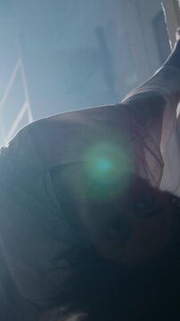 Disturbing contortionist woman in hospital gown convulsing and bending into back arch with insane stare in foggy dark corridor horror cinematic Halloween slow motion scene
