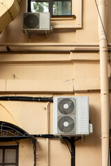 Air conditioners on the facade of yellow historical house. An air ventilation and cooling system and air purification technologies are installed. split system. cooling in hot weather. climate.