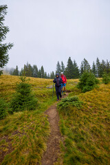 Naklejka premium tourists on a mountain trail on a cloudy autumn day