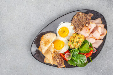 Breakfast plate with fried eggs, turkey, salad, and toast