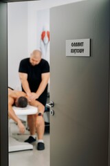 Fototapeta premium Massage therapy scene viewed through clinic door