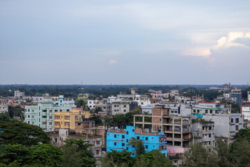 Fototapeta premium Scenic Kishoreganj, Bangladesh cityscape with modern high-rise buildings and verdant trees under an expansive afternoon sky. A perfect blend of urban development and nature.