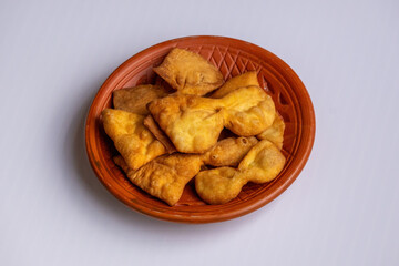 Homemade Bangladeshi Projapoti Pitha or Butterfly Cake on a clay plate. This sweet and crispy traditional snack is perfect for tea time or as a festive treat.