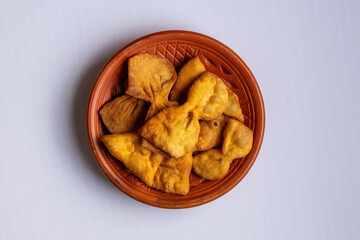 Top-down view of tasty, crispy homemade Projapoti Pitha (Butterfly Cake) on a clay plate, a popular sweet and traditional Bangladeshi snack perfect for tea time.