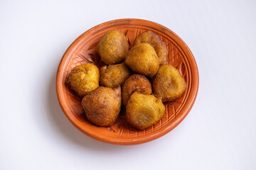 Homemade Bengali Taler Pitha or Taler Bora (palm fritters) on a traditional clay plate. This soft, spongy, and delicious sweet snack is a popular Bangladeshi delicacy.