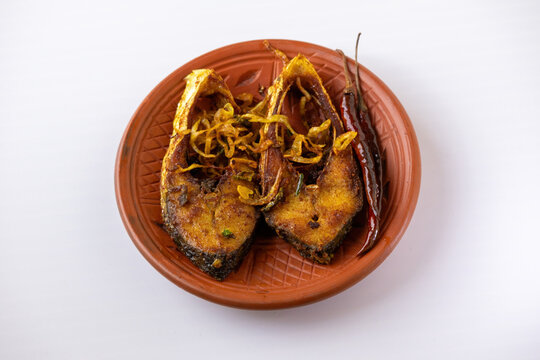Crispy hilsha fish fry (ilish bhaja) served with fried red chilies on a rustic clay plate. A traditional, iconic, and delicious Bengali meal.