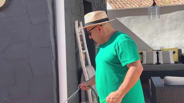 Plano medio de jardinero limpiando con manguera 4K