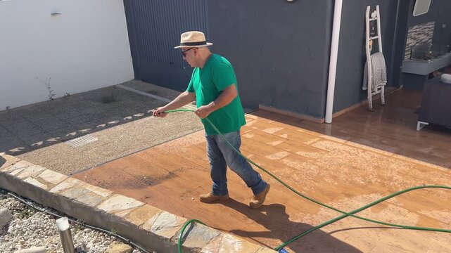 Plano general de un jardinero limpiando el suelo en casa mediterr&aacute;nea 4K