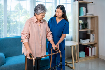 Caregiver assisting senior elderly woman with walker at home