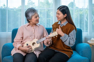 Senior Asian elderly woman playing ukulele with granddaughter giving support