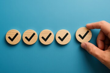 Hand carefully positions the final wooden checkmark, symbolizing successful project completion, achieving a major milestone with precision on a calming blue background