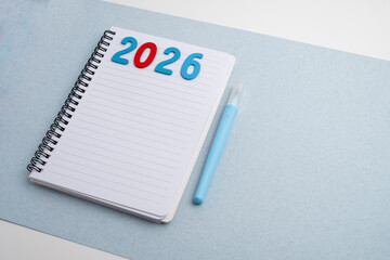 Happy New Year 2026 and a notepad on a colored background. Layout for writing annual business plans, schedules, as well as New Year's resolutions and goals.