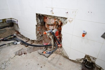 The plumbing work is currently in progress, showcasing exposed pipes and a bare floor in a bathroom renovation project