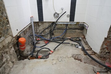 The plumbing work is currently in progress, showcasing exposed pipes and a bare floor in a bathroom renovation project